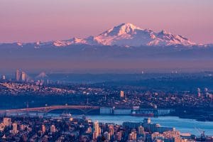 Scenic aerial view of West Vancouver with snowy mountains and city skyline at sunset.