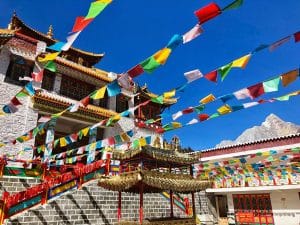Vibrant Tibetan monastery with prayer flags under a clear blue sky in Sichuan, China.