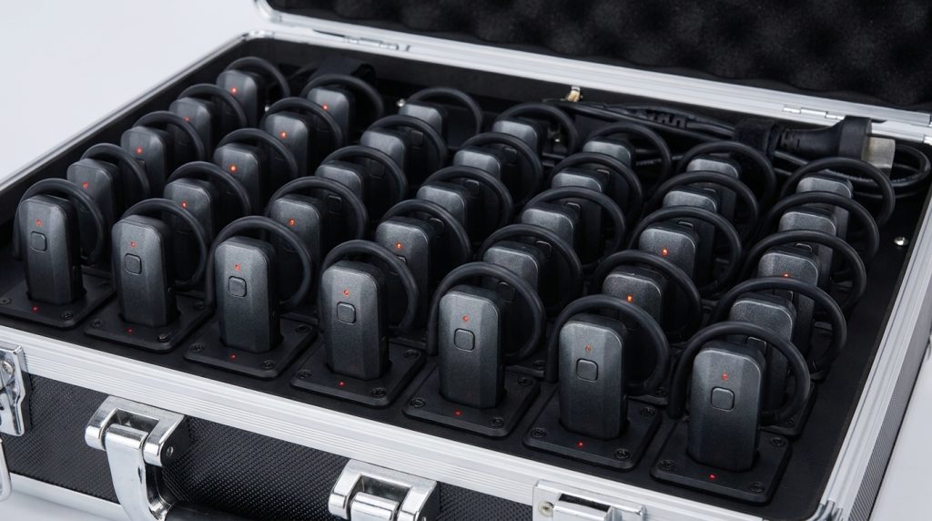 Rows of wireless tour guide receivers arranged in a charging case